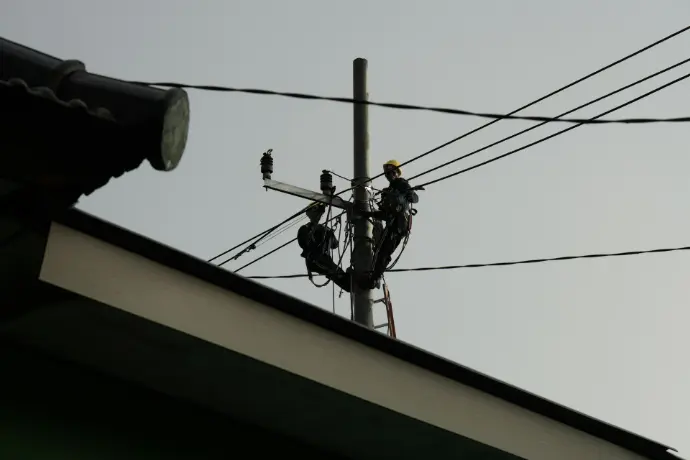 a power line with a man on a ladder working on it